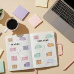 Laptop with Adobe Illustrator, open sketchbook with notes, coffee cup, colorful sticky notes, pencil, and potted succulent on beige surface.