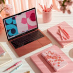 A stylish pink-themed workspace with a laptop, notebooks, pens, and flowers, showcasing an elegant, minimalistic design and aesthetic organization.