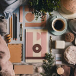 A flat lay of stationery, coffee, and decor items, featuring notebooks, pencils, a plant, and a cozy fabric, arranged aesthetically.